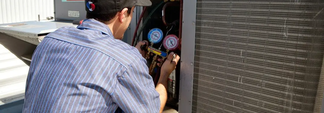 HVAC technician servicing a condenser unit in Hopedale